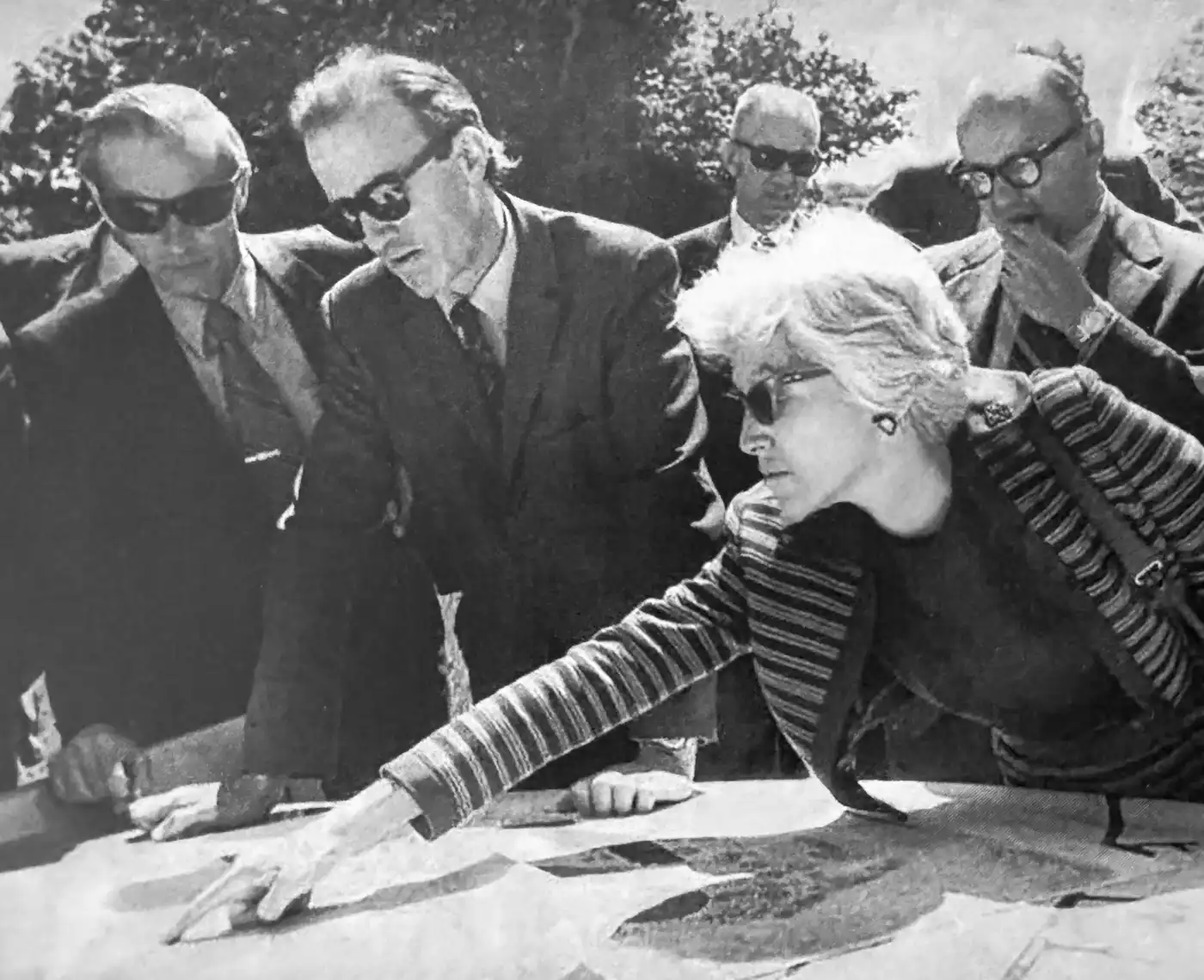 Elizabeth Scheu Close pointing at plans on a table, with colleagues looking on
